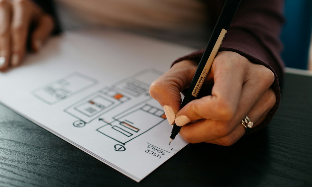 Designer sketching interface wireframes to simplify user journeys and interactions